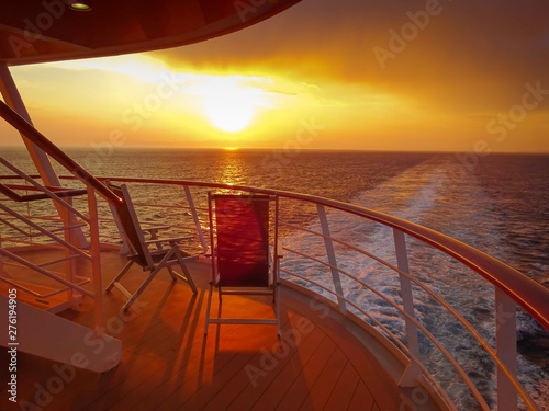 Vue de deux chaises longues sur le pont d'un navire de croisière au coucher de soleil dans le sillage du navire de croisière. Vue depuis la poupe du navire. © ODIN Daniel