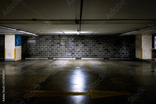 Parking lot cars in building with light and dirty brick wall background