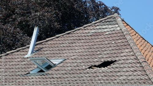 Hole in the roof of a house. Roof damage. Broken tile roof after a storm.