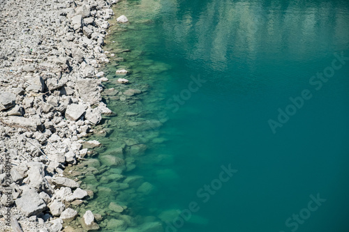 Clear turquoise water surface with stones on the beach