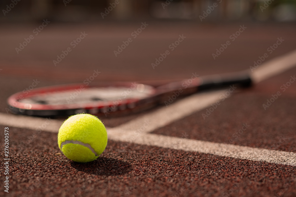 Yellow tennis ball on sports playground and tennis racket