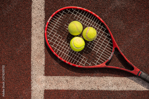 Top view of three tennis balls on racket on sports playground