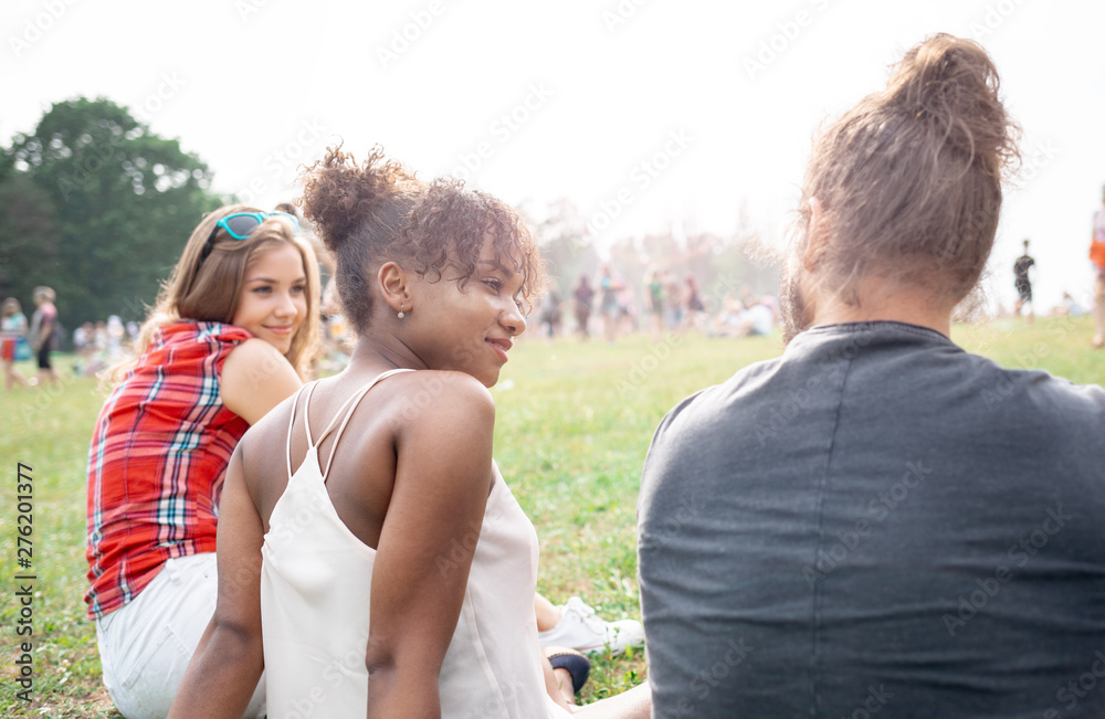 Friends sitting on grass and having fun at music festival