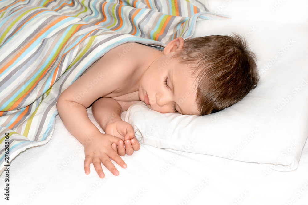 Sleeping baby on white background. Toddler boy sleeps on white pillow under blanket