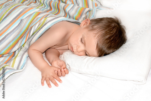Obraz na płótnie Sleeping baby on white background. Toddler boy sleeps on white pillow under blanket w salonie