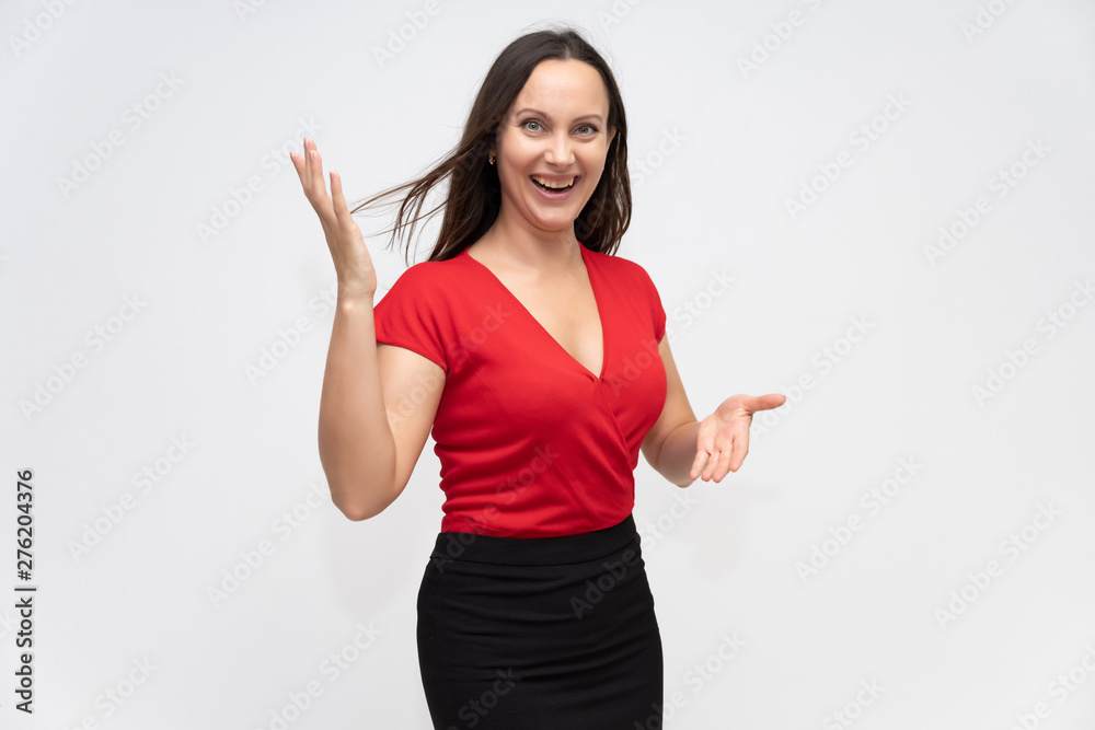 Portrait to the waist of a young pretty brunette woman of 30 years old in a bright red sweater with beautiful dark hair. Standing on a white background, talking, showing hands, with emotions Portrait to the waist of a young pretty brunette woman of 30 years old in a bright red sweater with beautiful dark hair. Standing on a white background, talking, showing hands, with emotions