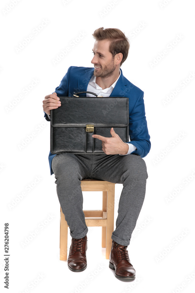 Cheerful businessman pointing to his briefcase and smiling Cheerful businessman pointing to his briefcase and smiling