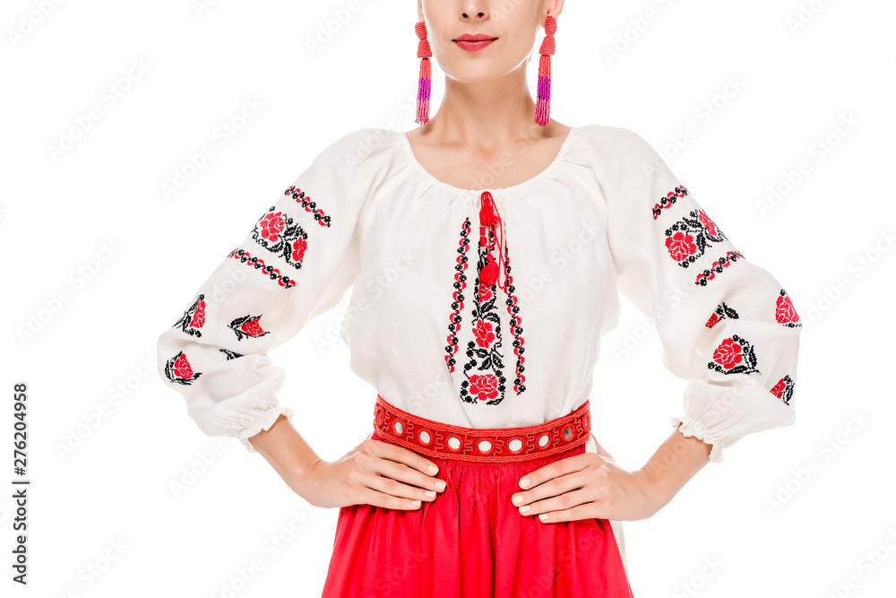 cropped view of young woman in national Ukrainian costume standing with hands on hips isolated on white