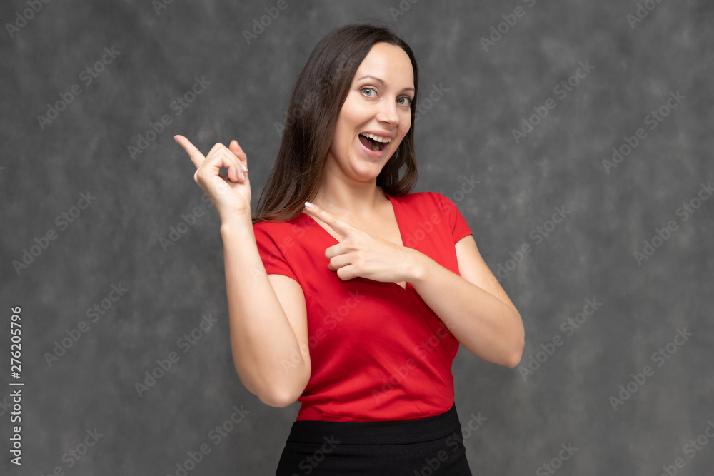 Portrait to the waist of a young pretty brunette woman of 30 years old in a bright red sweater with beautiful dark hair. It is standing on a gray background, talking, showing hands, with emotions Portrait to the waist of a young pretty brunette woman of 30 years old in a bright red sweater with beautiful dark hair. It is standing on a gray background, talking, showing hands, with emotions
