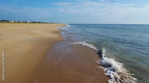 A 4k drone aerial view of a coastal beach in Virginia. flying forward seeing a birds-eye view of a bike and beachgoers walking along the beach with the waves crashing onto the sand. Water is turquoise photo