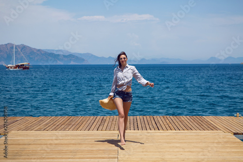 young sexy woman in a hat standing on the sea at the pier