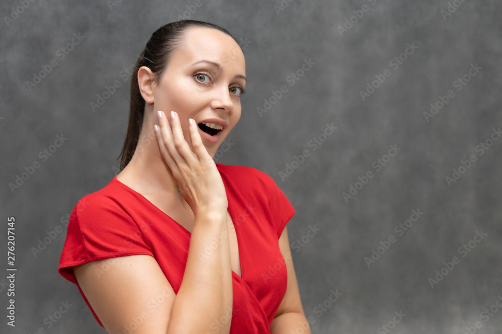 portrait of a young fashionable pretty brunette woman 30 years old with beautiful dark hair in a red sweater. On a gray background, smiling, showing emotions. portrait of a young fashionable pretty brunette woman 30 years old with beautiful dark hair in a red sweater. On a gray background, smiling, showing emotions.