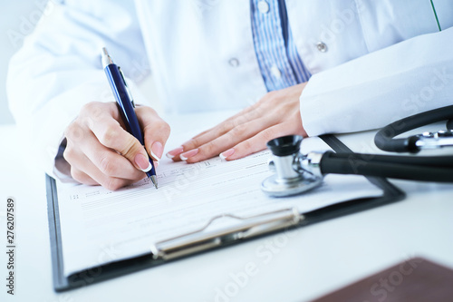Medicine doctor hand holding silver pen writing something on clipboard closeup.. Ward round, patient visit check, medical calculation and statistics concept.