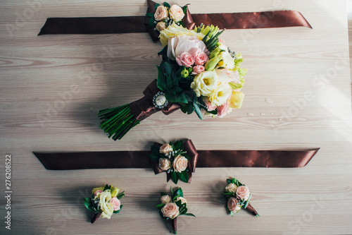 beautiful tender wedding bouquet of cream roses, eustoma flowers. Decorations, buttonholes, bracelet on hand with brown ribbons. made of roses, decorative plants. Close up. handmade floral accessory photo