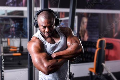 The athlete listens to music on headphones from his smartphone in the gym