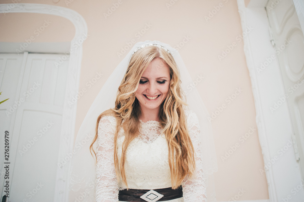 A stylish elegant happy and smiling bride. Good hairstyle and makeup. Portrait of a women. bride stand on background of wall, white doors. Close up. Portrait. Retro. Vintage architecture indoors.