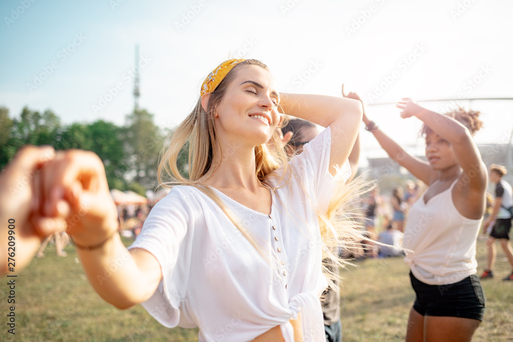 Obraz premium Beautiful young long haired woman dancing with friends outdoor at music festival