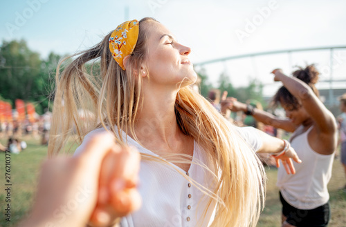 Beautiful young long haired woman dancing with friends outdoor at music festival
