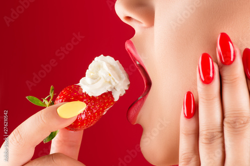 woman with sensual lips eats strawberries with cream