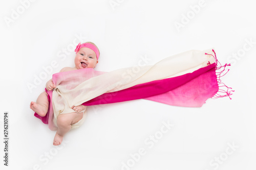 Top view of cute baby girl dressed in a fairy costume sticking out her tongue- fluttering long scarf and headband. Space for text