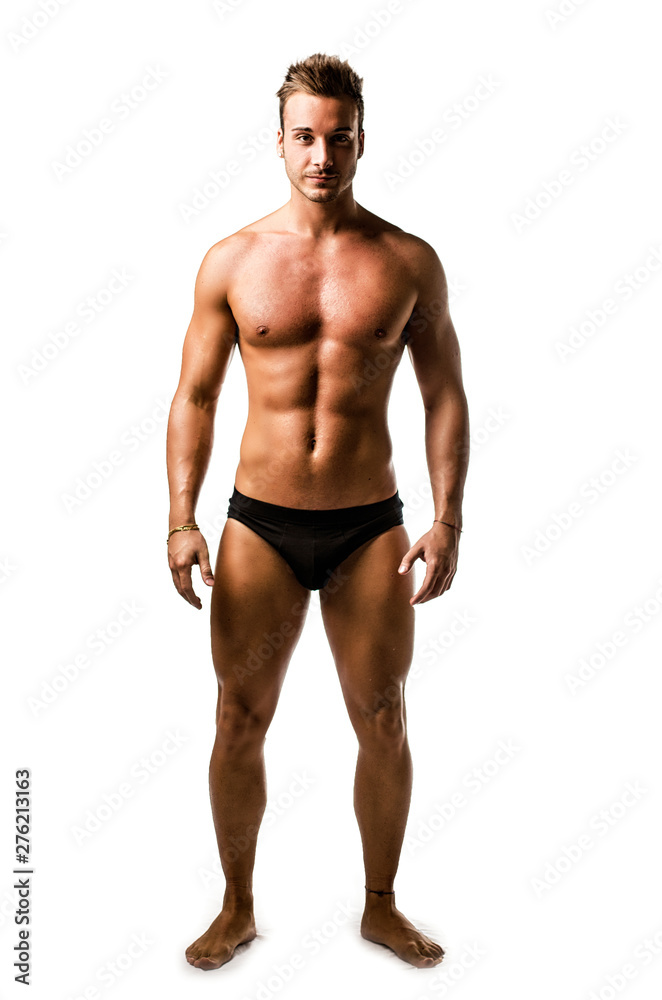 Full length body shot of handsome, fit young man wearing only underwear standing isolated on white background, looking at camera