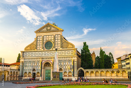 Basilica di Santa Maria Novella and green grass lawn with flowers on Piazza Santa Maria Novella square in historical centre of Florence city, blue sky white clouds, Tuscany, Italy
