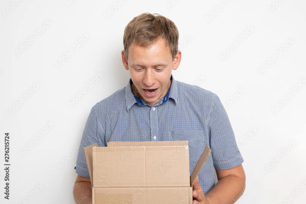 curious man looking inside a cardboard box he holds in his hands on a white background curious man looking inside a cardboard box he holds in his hands on a white background