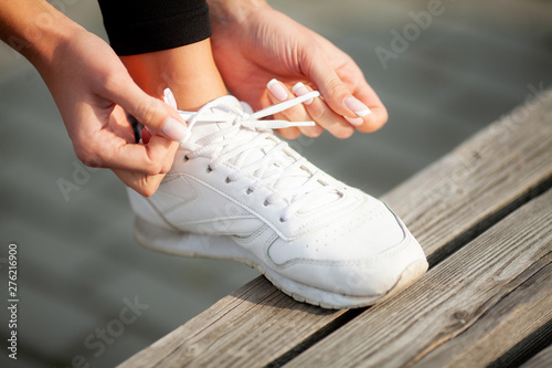 Woman Runner Tightening Shoe Lace. Runner Woman Feet Running On Road Closeup On Shoe
