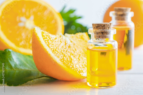 Photography Natural orange essential oil in bottle and cut oranges fruit on white wooden table