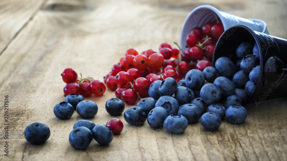 Combination of blueberries and cranberries rolled over on wooden table Combination of blueberries and cranberries rolled over on wooden table