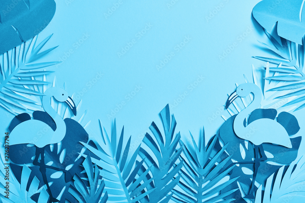 Fototapeta widok z góry na niebieskie egzotyczne wycięte z papieru liście palmowe i flamingi na niebieskim tle z miejscem na kopię
