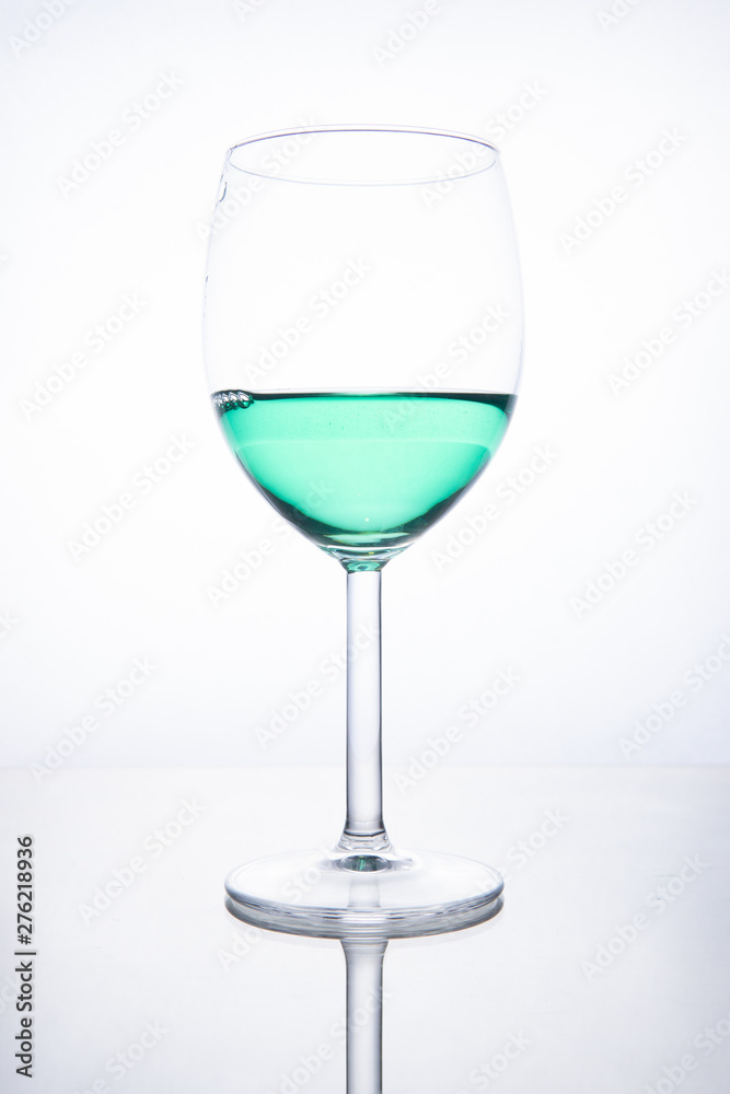 Green cocktail in a glass on a white background with reflection