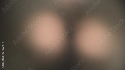 Unrecognizable scary and naked man looking behind a frosted glass carefully.