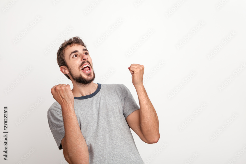 Excited man with wide open mouth cheers with raised hands and fists clenched Excited man with wide open mouth cheers with raised hands and fists clenched