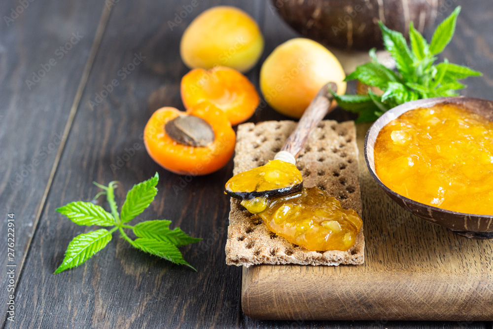 Apricot jam in a wooden bowl and fresh apricots on a wooden background. Copy space. Summer harvest concept. Apricot jam in a wooden bowl and fresh apricots on a wooden background. Copy space. Summer harvest concept.