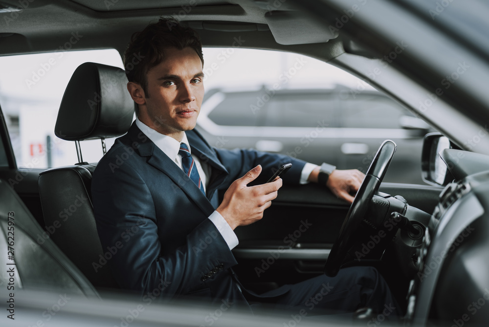 Young handsome man holding mobile phone in his car