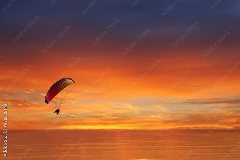 colored parachute flies in the sky against the backdrop of the sea at sunset, Zen, harmony, balance. ocean at sunset in the background travel, flight, vacation Concept