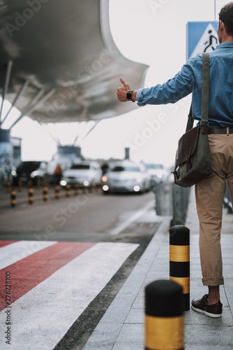 Man in casual wear standing with bag near entrance in airport