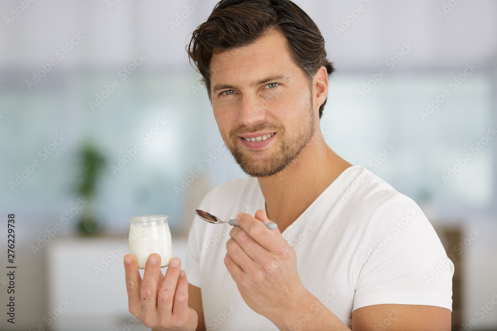 man is eating a yogurt - obrazy, fototapety, plakaty 