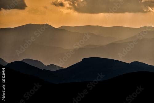 Silhouettes of mountains against the background of an orange sky. Sunset in the mountains. Geghama Mountains. Armenia photo