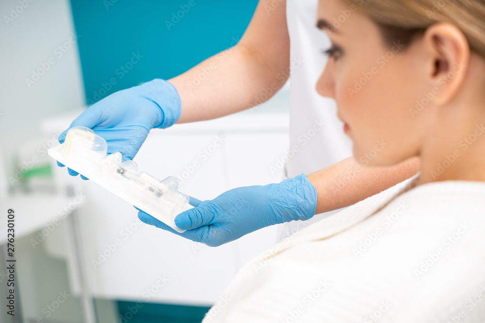 Cosmetologist showing injection set to the female patient Cosmetologist showing injection set to the female patient