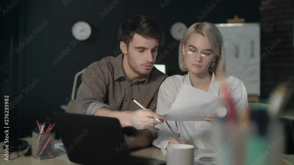 Business couple working on financial project in dark office together. Business couple working on financial project in dark office together.