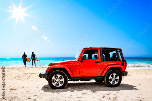 Summer red car on beach and sea landscape with blue sky and sun . 