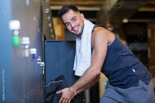 smiling man opening locker in the gym