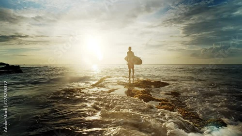 A man is standing with a surf in his hands on the sea shore.