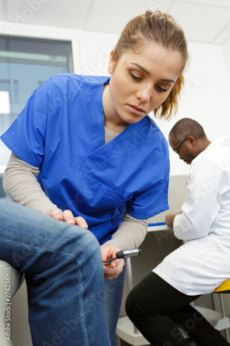 female neurologist testing knee reflex with a hammer