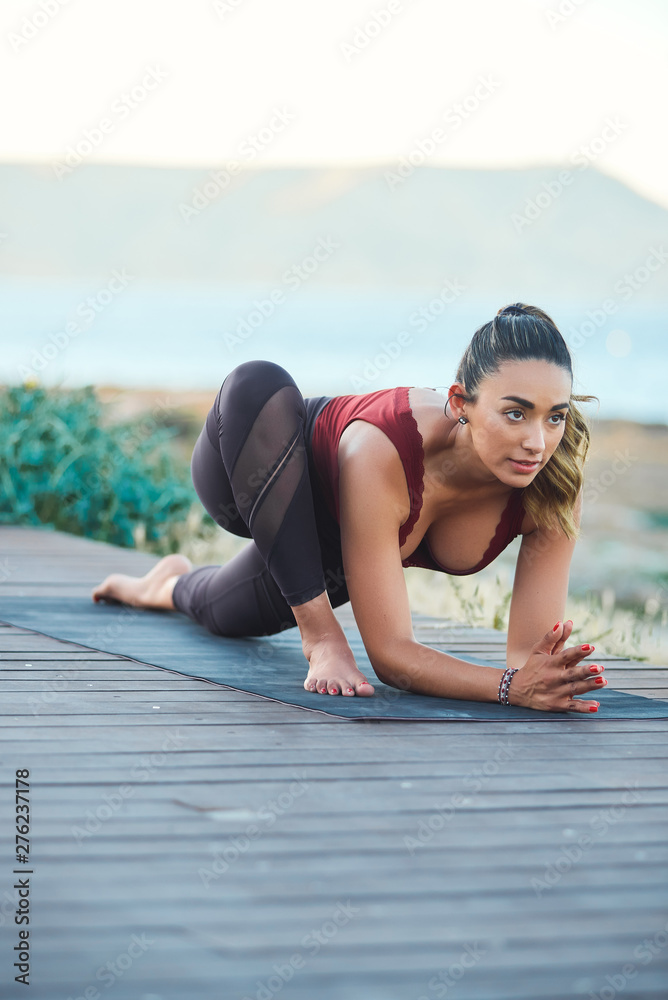 Portrait of beautiful young woman making yoga exercises on the beach.
