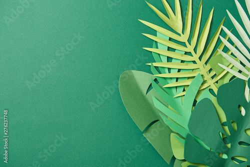 top view of tropical paper cut palm leaves on green background with copy space photo