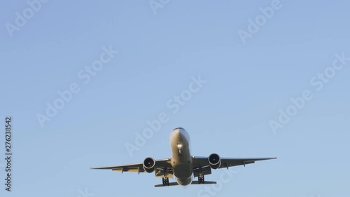 Commercial passenger airplane flying overhead on sunny day. photo