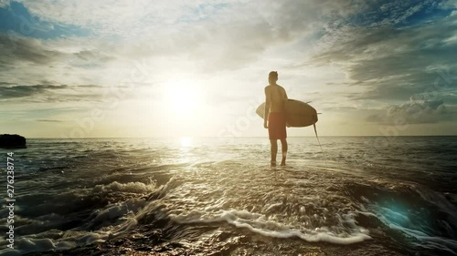A man is standing with a surf in his hands on the sea shore. photo